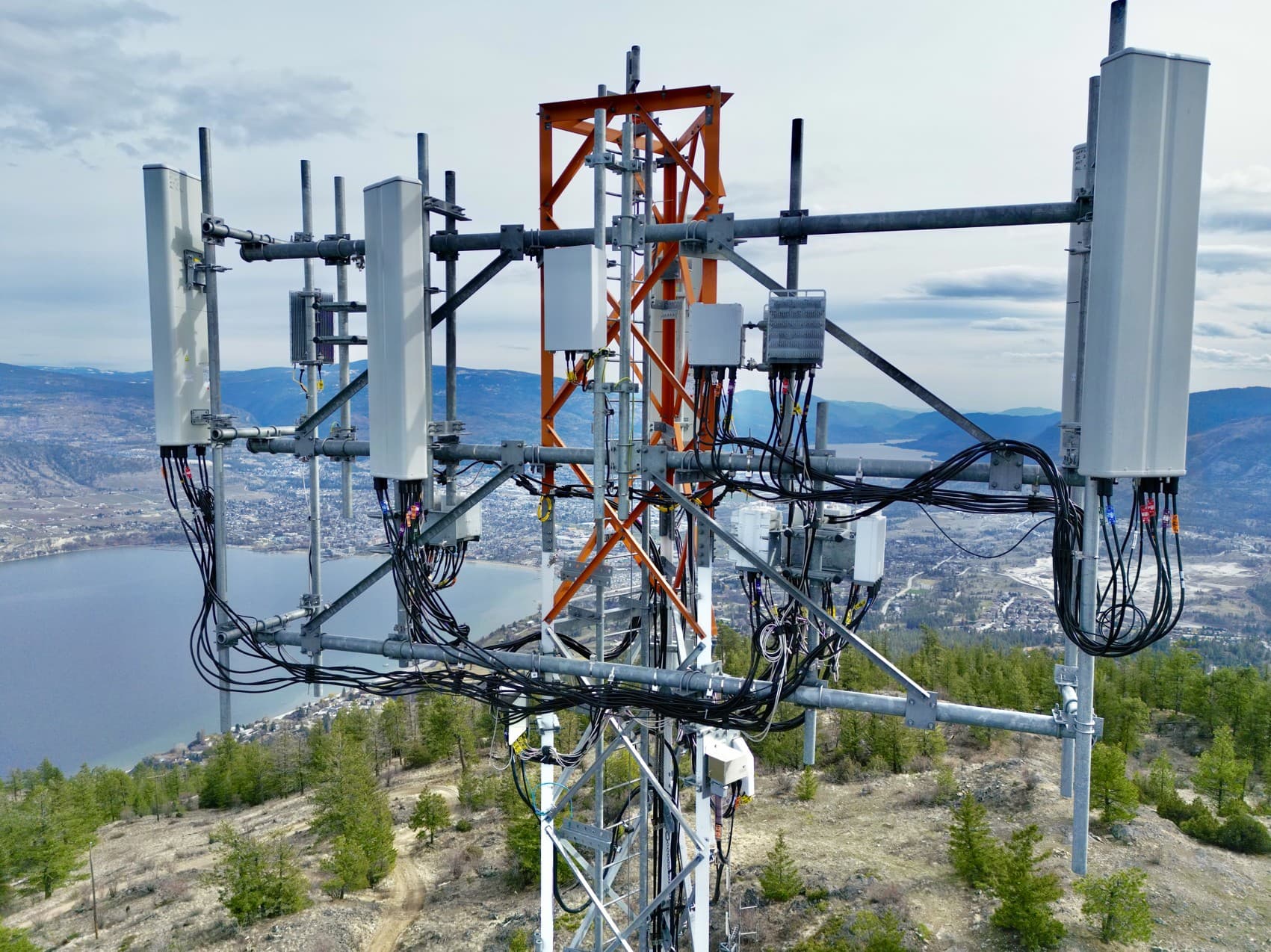Drone inspection of communication tower with antennas and equipment mounted high above terrain
